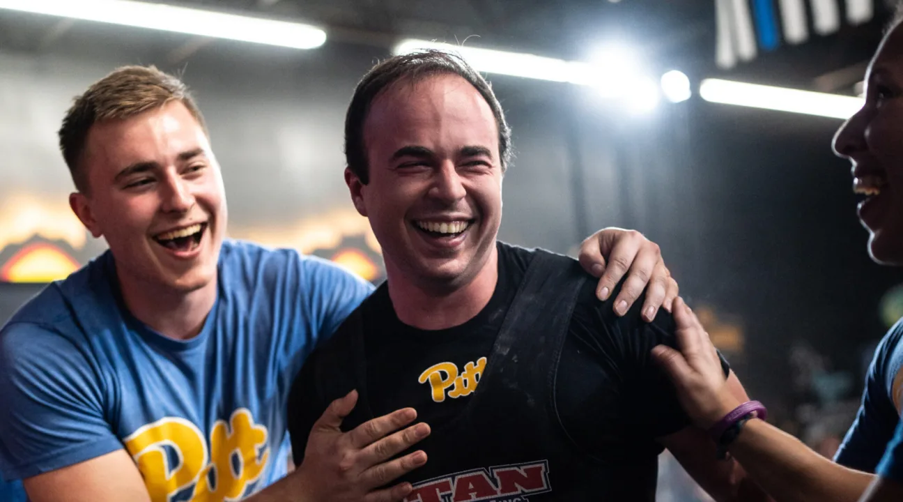 A powerlifter being congratulated by other powerlifters.