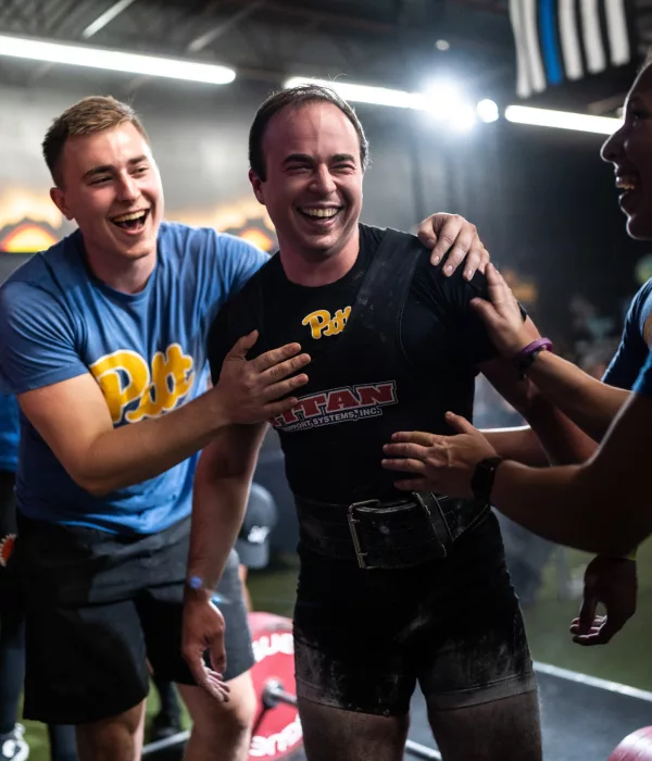 A powerlifter being congratulated by other powerlifters.